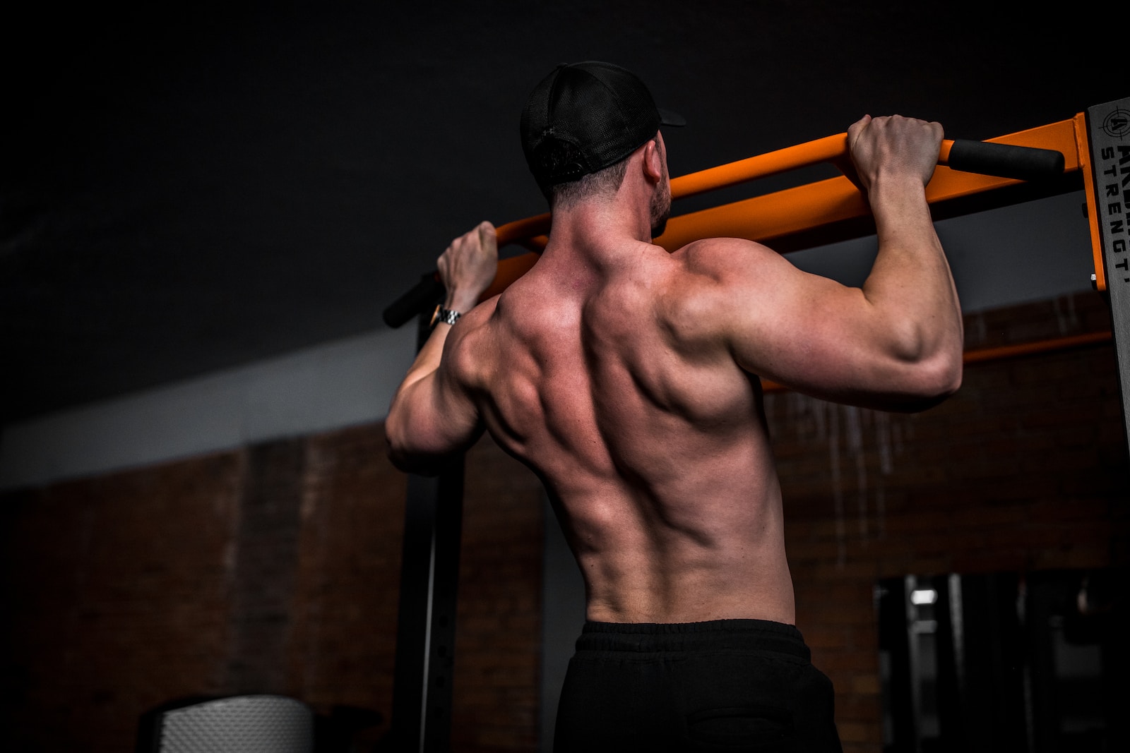 topless man in black shorts holding orange bar